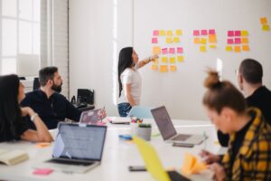 Equipe de e-commerce planejando campanhas em uma parede de post-its durante reuniao de estrategia