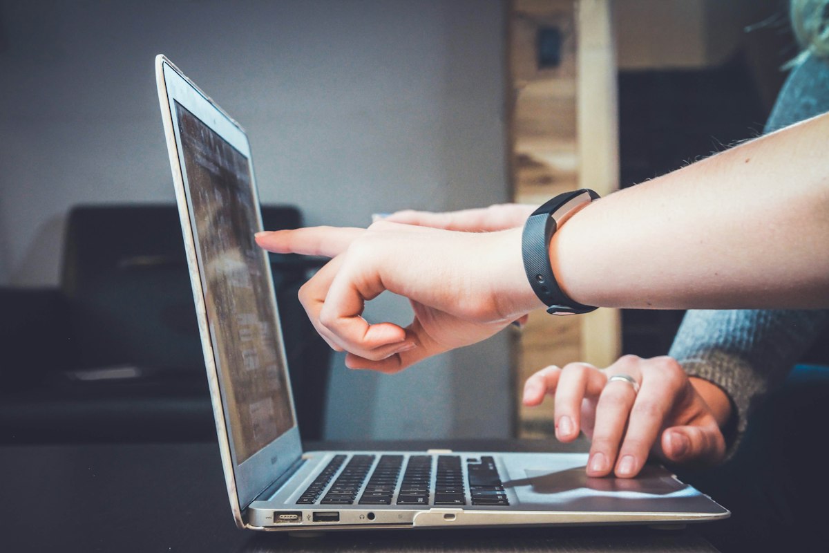 Duas pessoas apontando para a tela de um notebook enquanto analisam dados da loja virtual