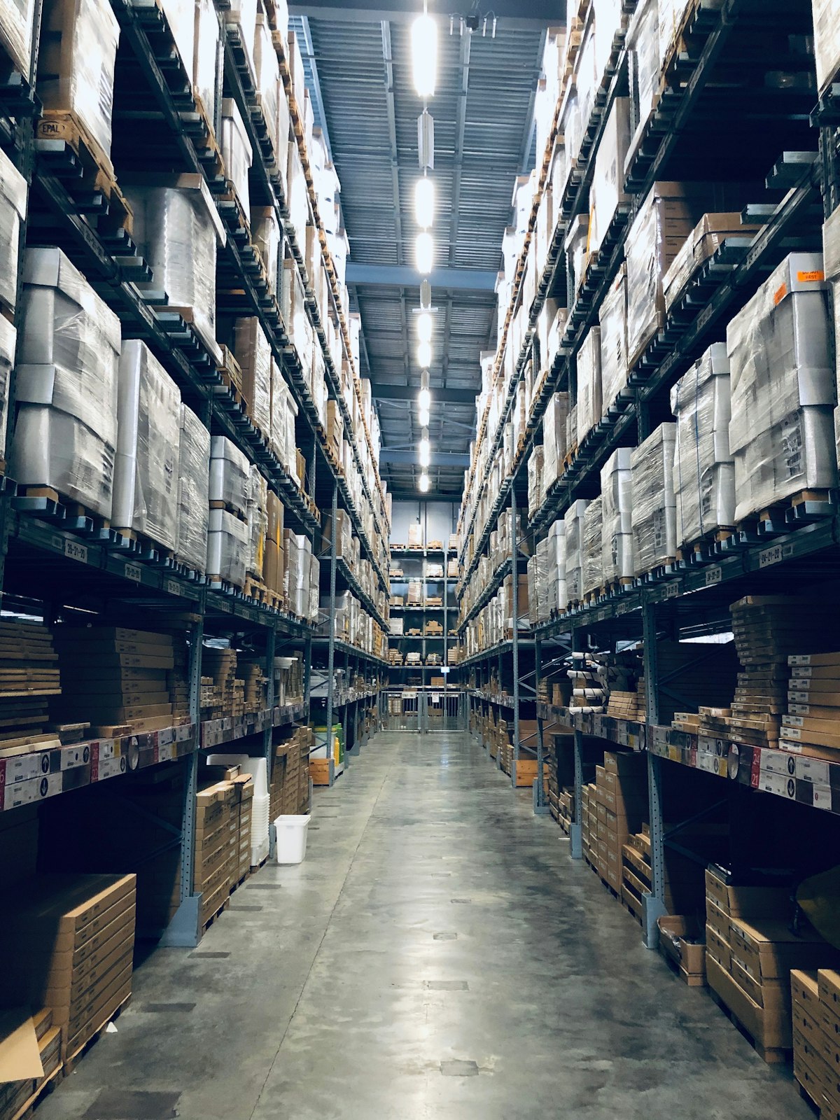 Corredor de estoque de e-commerce com prateleiras altas e paletes de produtos