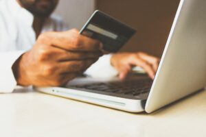 Consumidor com cartao de credito na mao finalizando uma compra no notebook